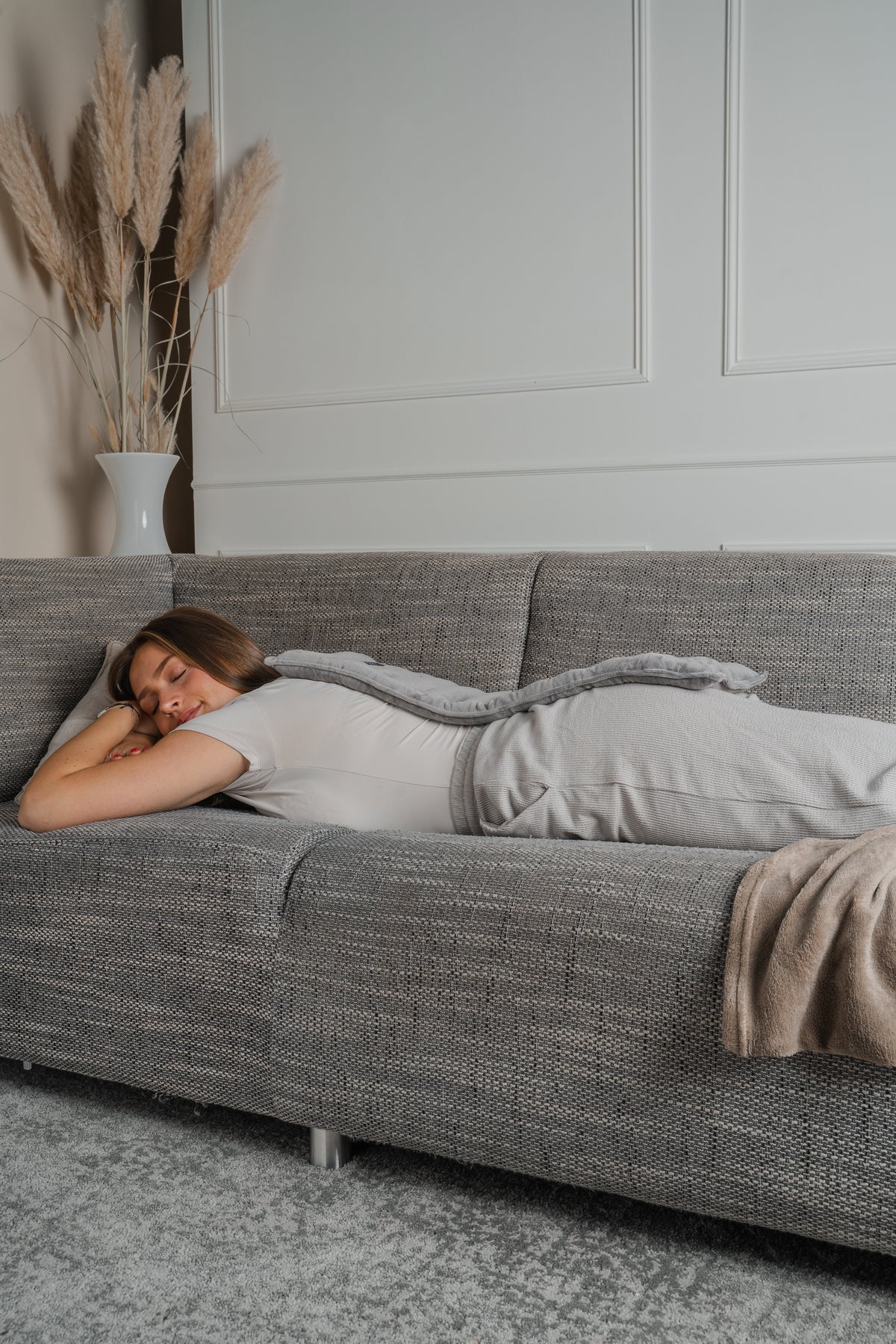 Vrouw rust op de bank onder een lang warmtekussen